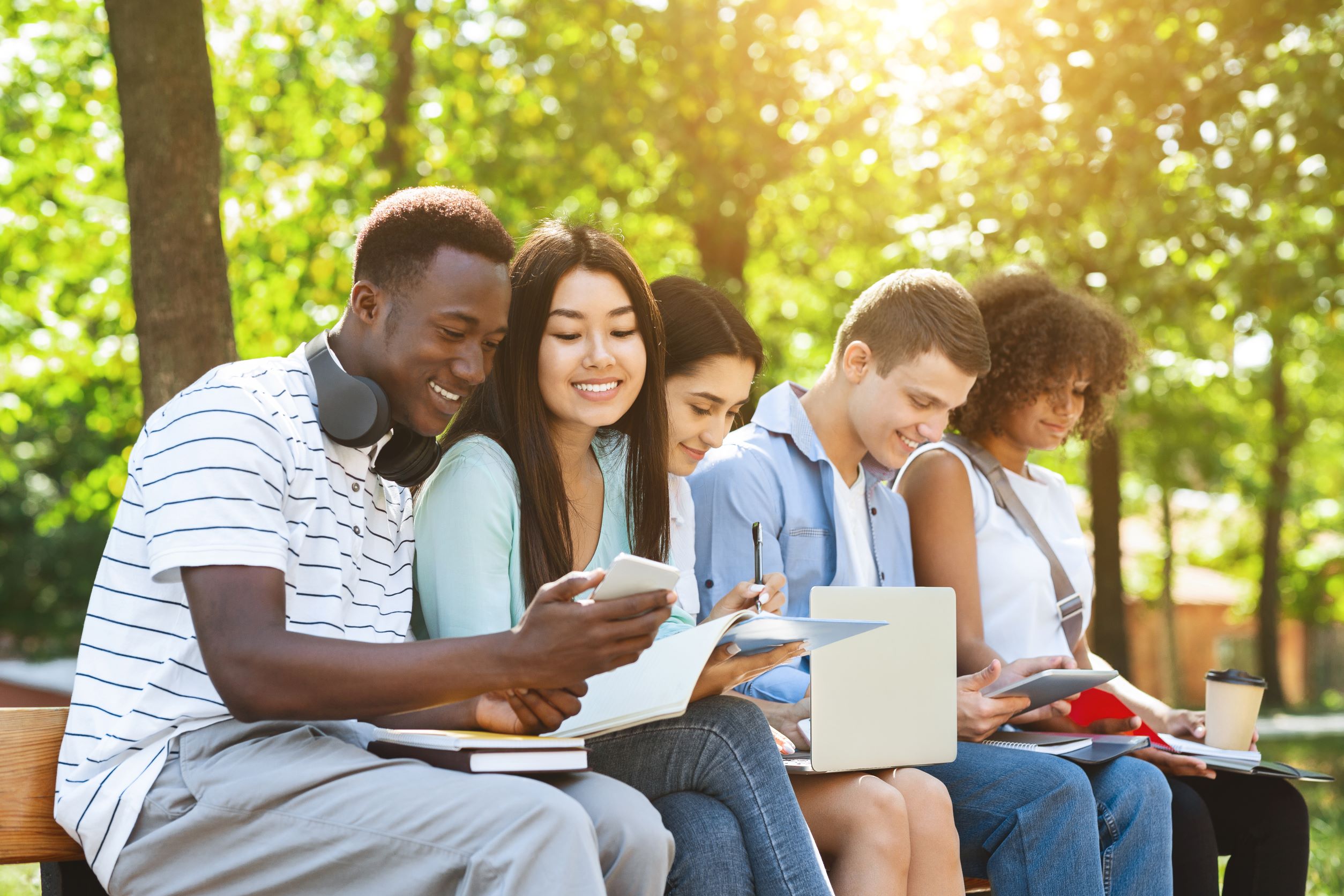 Group of young people sits outside on their devices